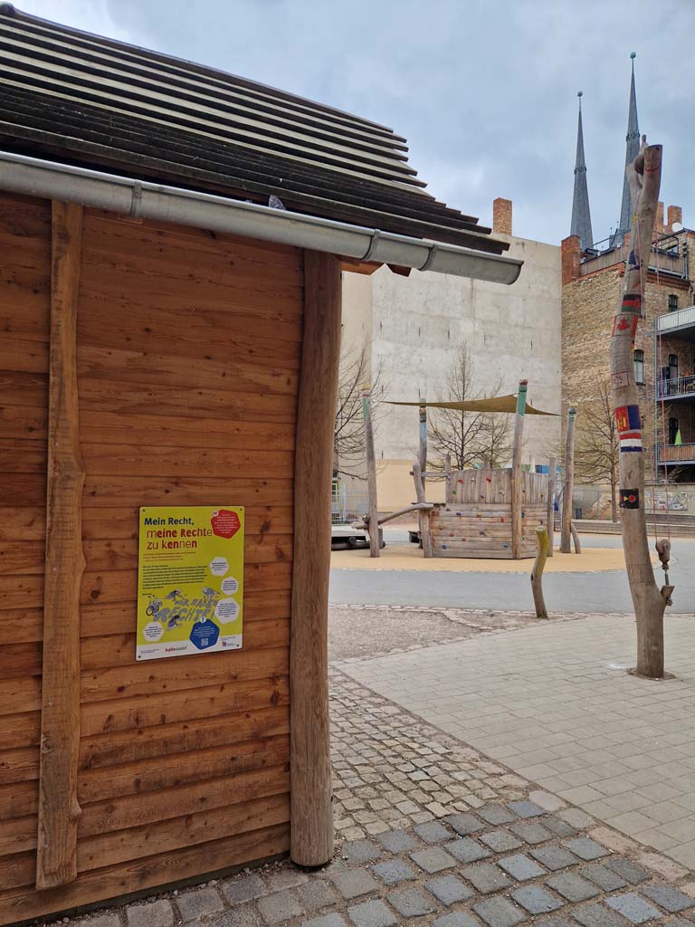 Station 4 - Lyonel-Feininger-Gymnasium, Tafel zum Thema: Recht, meine Rechte zu kennen an einer Holzwand auf dem Schulhof