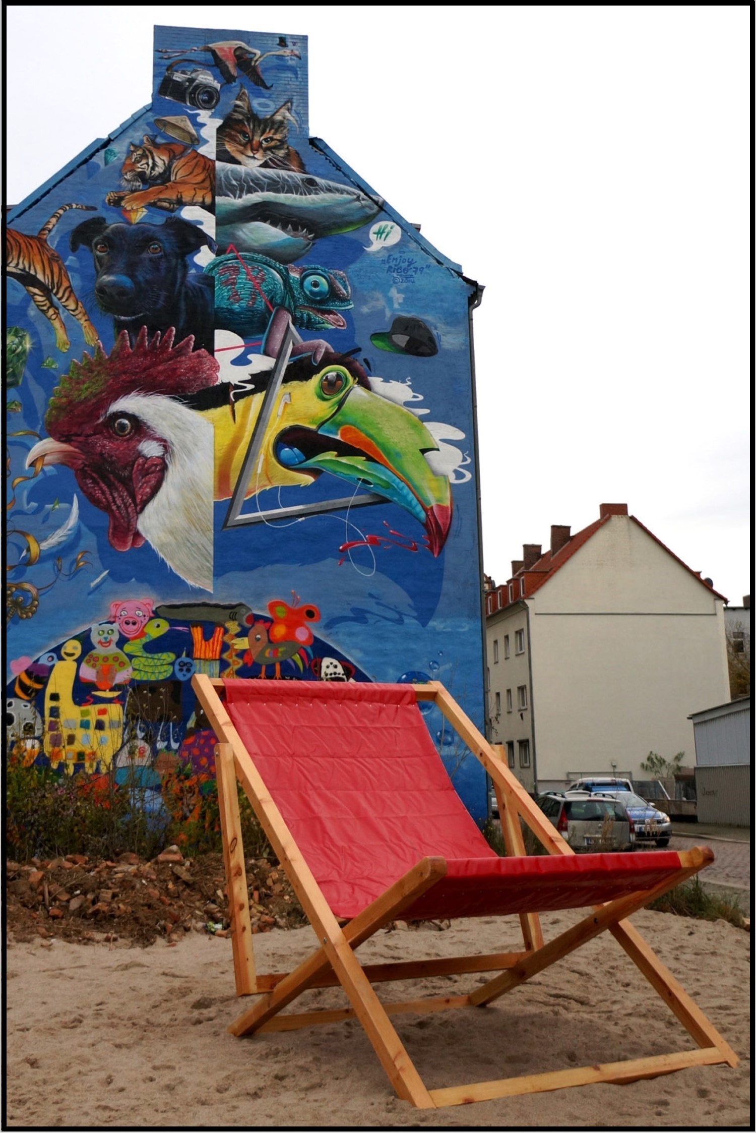 ein roter, leerer Liegestuhl steht auf Sand in der Landsberger Straße