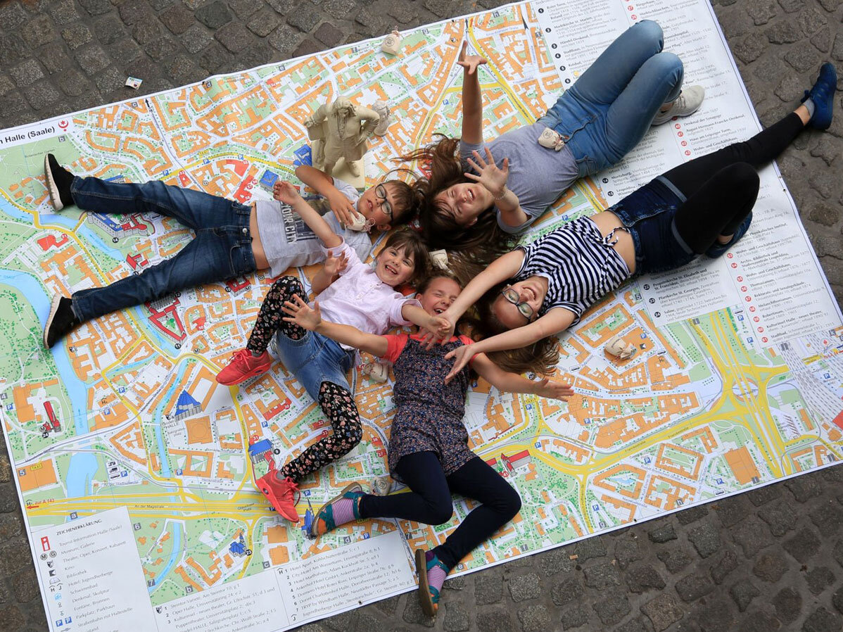 5 Kinder liegen auf einem Stadtplan von Halle