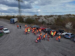 Foto aus Luftperspektive, das zahlreiche Mitarbeitende der Stadtwerke zeigt, die mit Warnwesten und Müllsäcken ausgestattet sind.