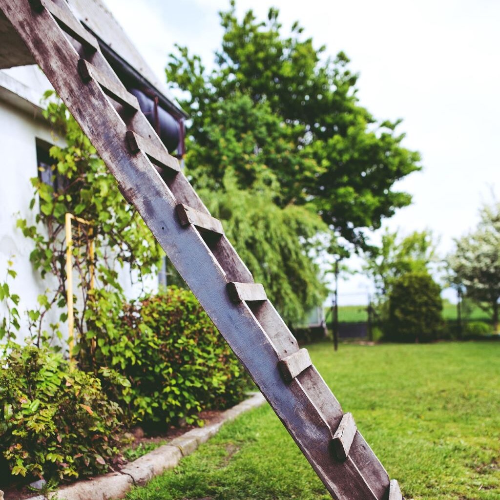 eine alte Holzleiter lehnt an einem Haus