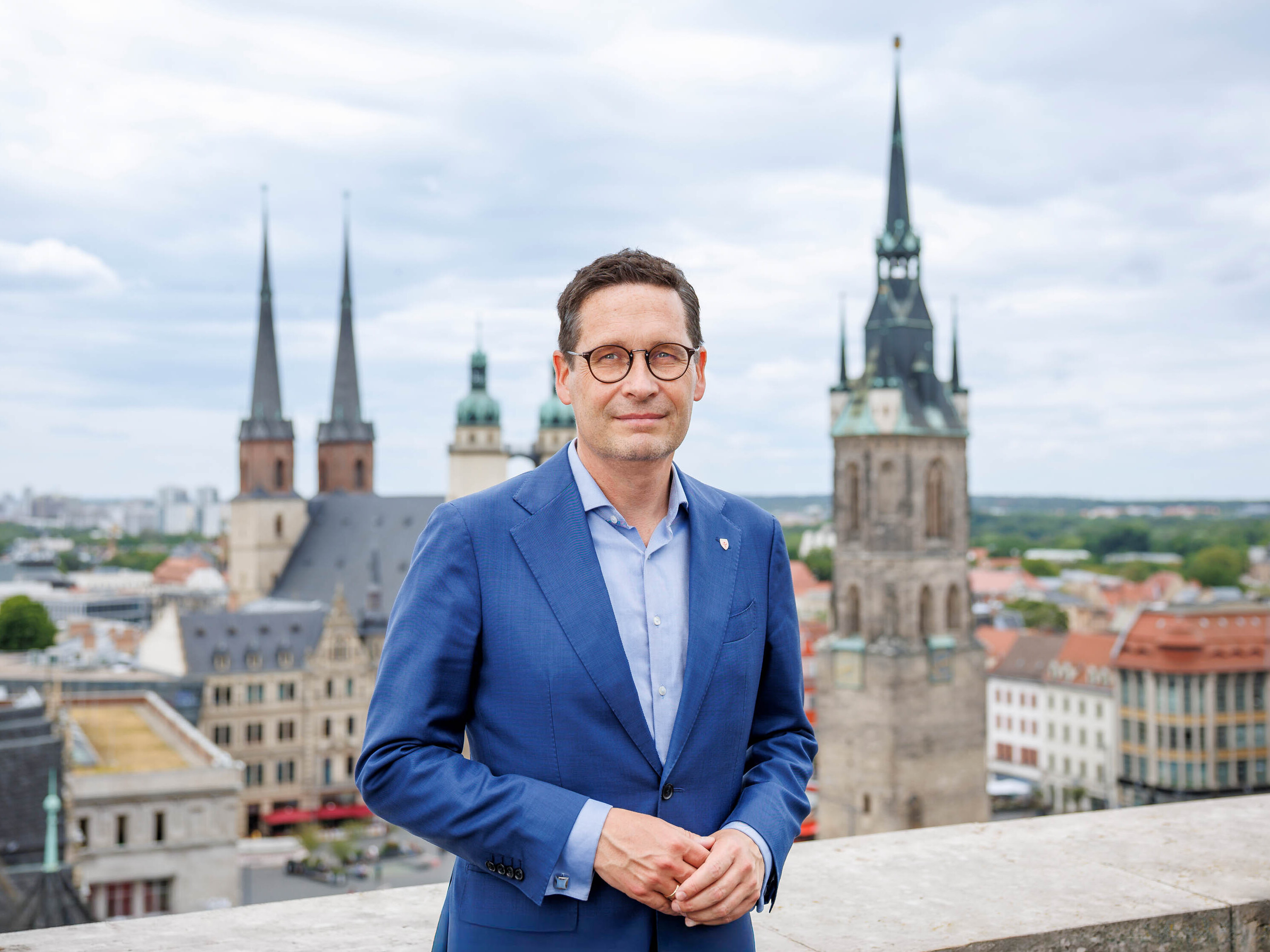 Porträtfoto Oberbürgermeister Dr. Alexander Vogt mit Markt von Halle im Hintergrund