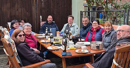 Gesellige Runde mit mehreren Personen, die an einem Tisch sitzen.