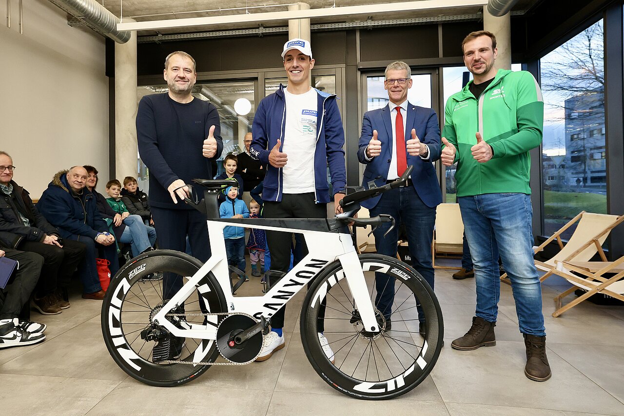 vier Männer vor einem Rennrad