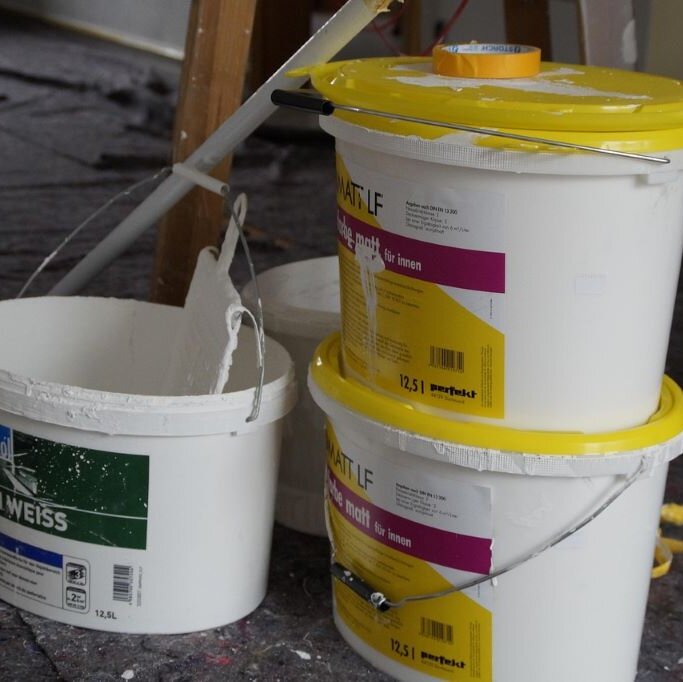 drei weiße Farbeimer mit gelben Deckel