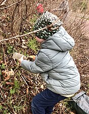 Ein Kind hebt eine Glasflasche auf.