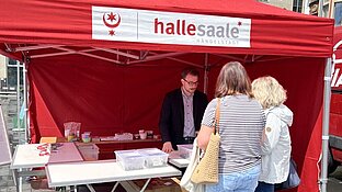 ein Mann im Zelt spricht mit zwei Frauen