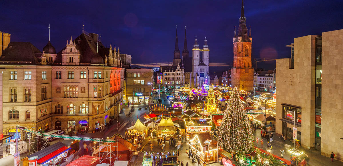 Blick auf den Weihnachtsmarkt auf dem Halleschen Marktplatz am Abend mit beleuchtetem Baum