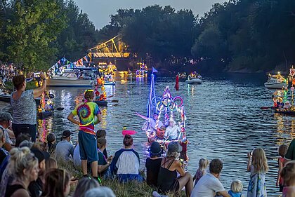Beleuchtete und geschmückte Boote abends auf der Saale.