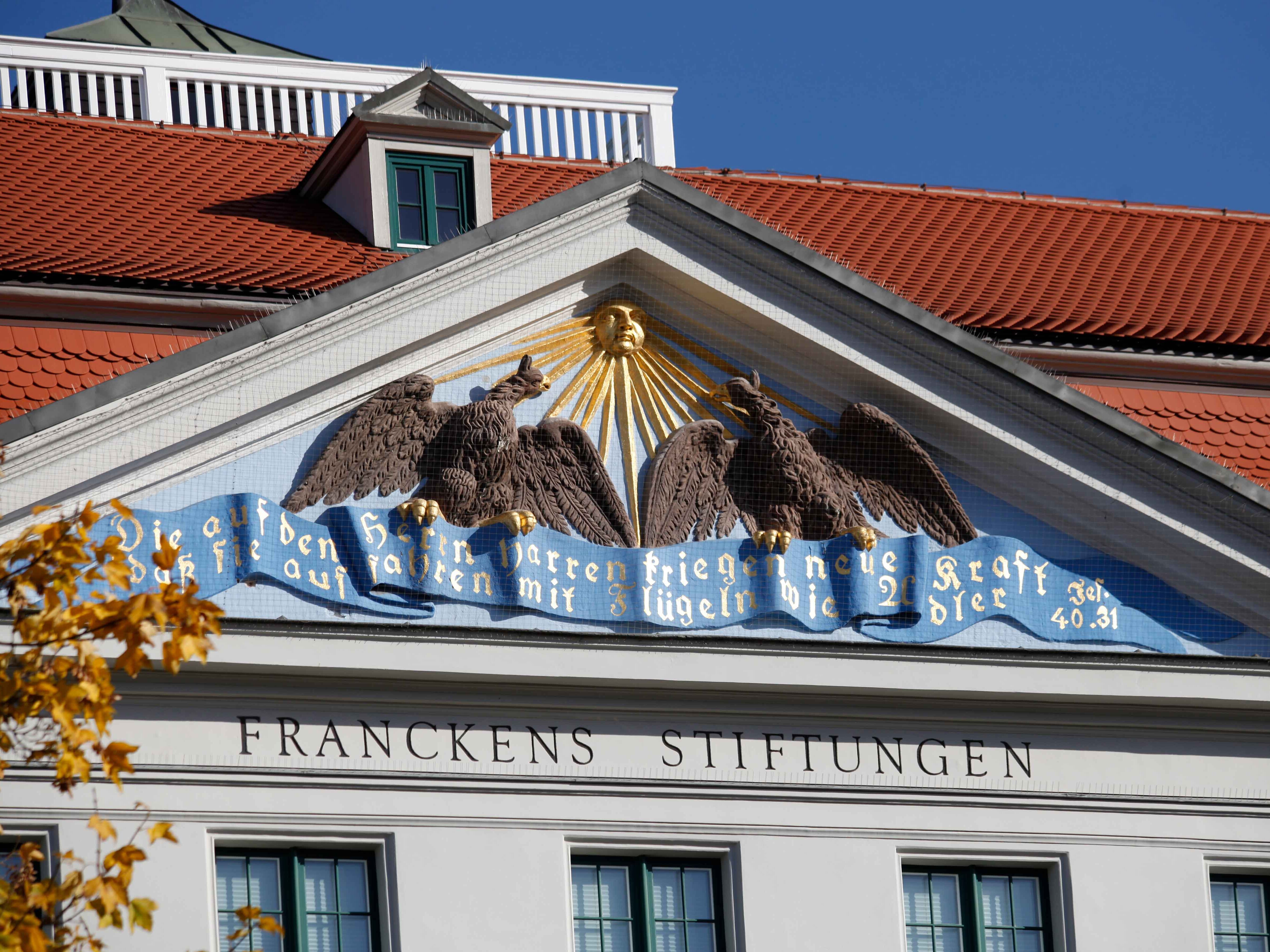 Nahaufnahme des Wandbildes am Eingang der Franckeschen Stiftungen - eine goldene Sonne mit zwei Adlern, die auf einem blauen Banner sitzen
