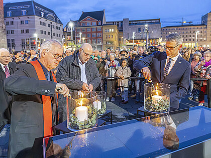 Drei Männer entzünden Kerzen