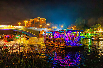 bunt beleuchtete Boote auf der Saale, im Hintergrund Giebichensteinbrücke und Burg Giebichenstein