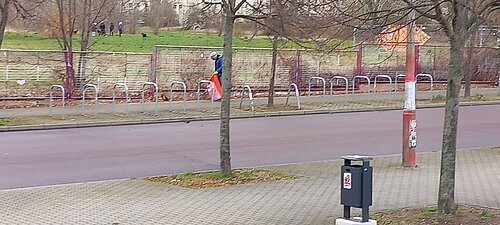 Foto der Kantstraße, wo im Hintergrund eine Person zu sehen ist, die Streumüll mit einer Greifzange aufliest.
