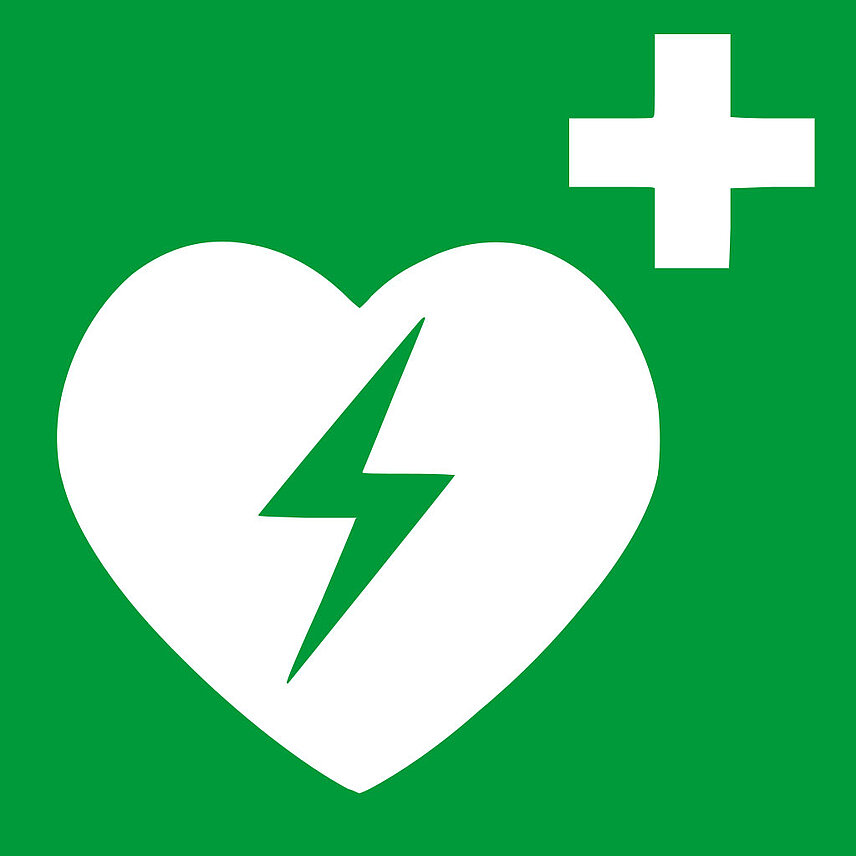 weißes Herz mit elektronischem Blitz auf grünem Untergrund. In der Ecke oben rechts medizinisches Kreuz