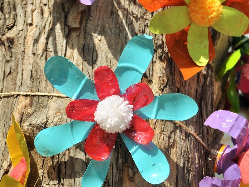 bunte Plastikblumen an einem Baum befestigt