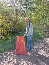 Ein Mann mit Müllsack in der Hand sammelt Müll.