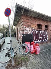 An einem Häuschen stehen befüllte Müllsäcke.