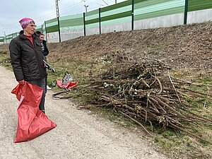 Zwei Frauen stehen mit Müllsack in der Hand vor einem großen Gehölzhaufen.