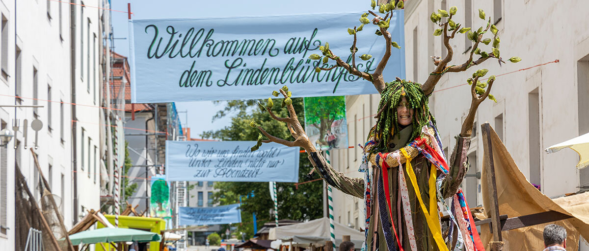 Eine als Linde verkleidete Frau geht durch den Markt im Innenhof der Franckeschen Stiftungen