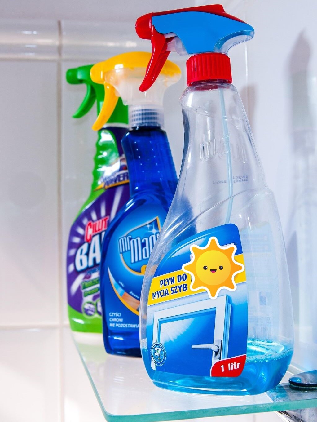 drei Plastiksprühflaschen auf einem Wandregal