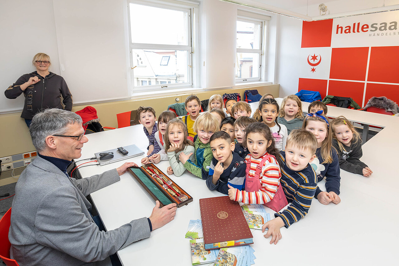 Bürgermeister Egbert Geier zeigt einer Gruppe Kindern die Amtskette des halleschen Oberbürgermeisters in einem Kasten 