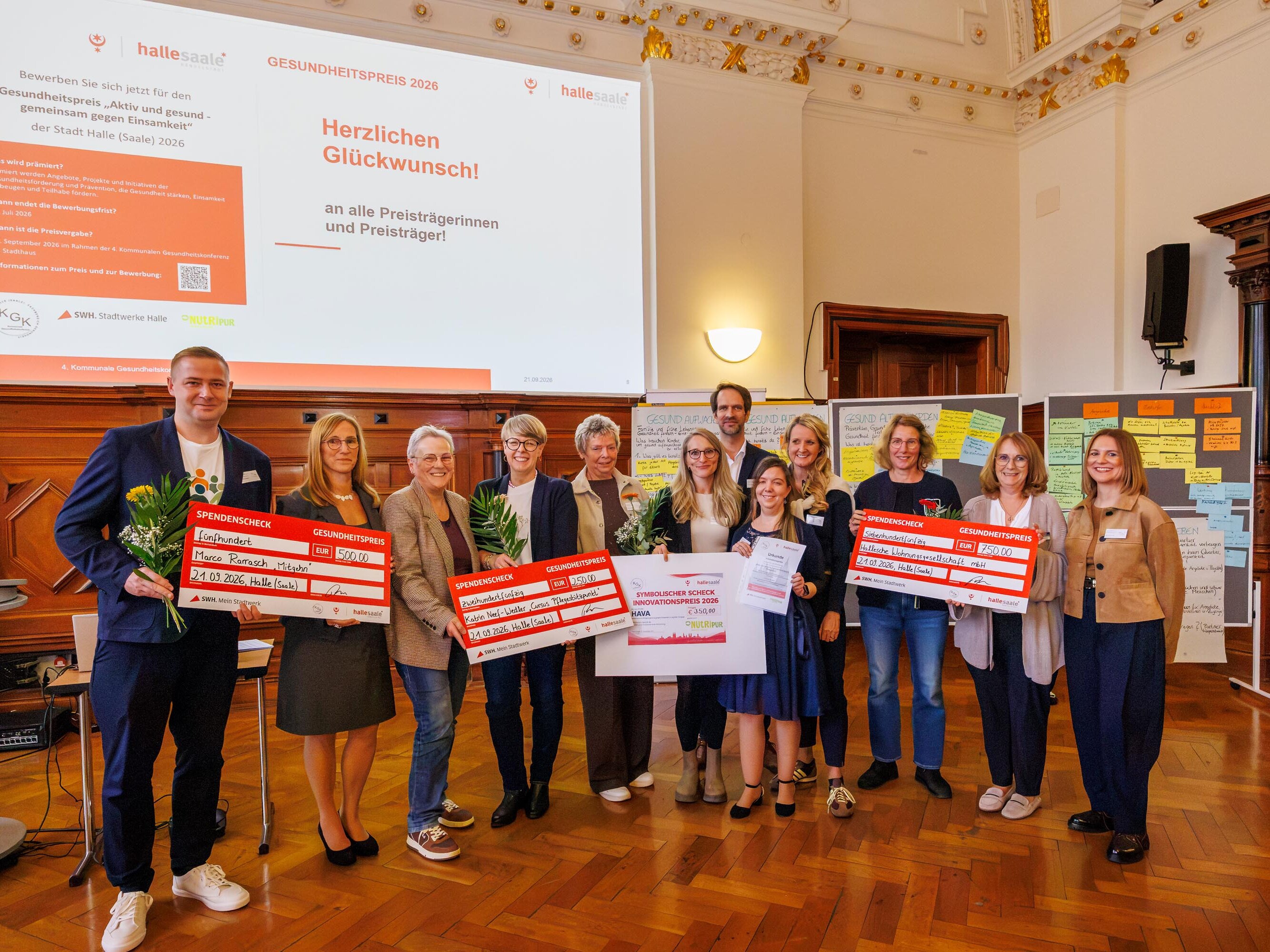 Gruppenfoto der Ausgezeichneten des Gesundheitspreises 2026 der Stadt Halle (Saale) mit Blumen und Preischecks bei der 4. Kommunalen Gesundheitskonferenz.