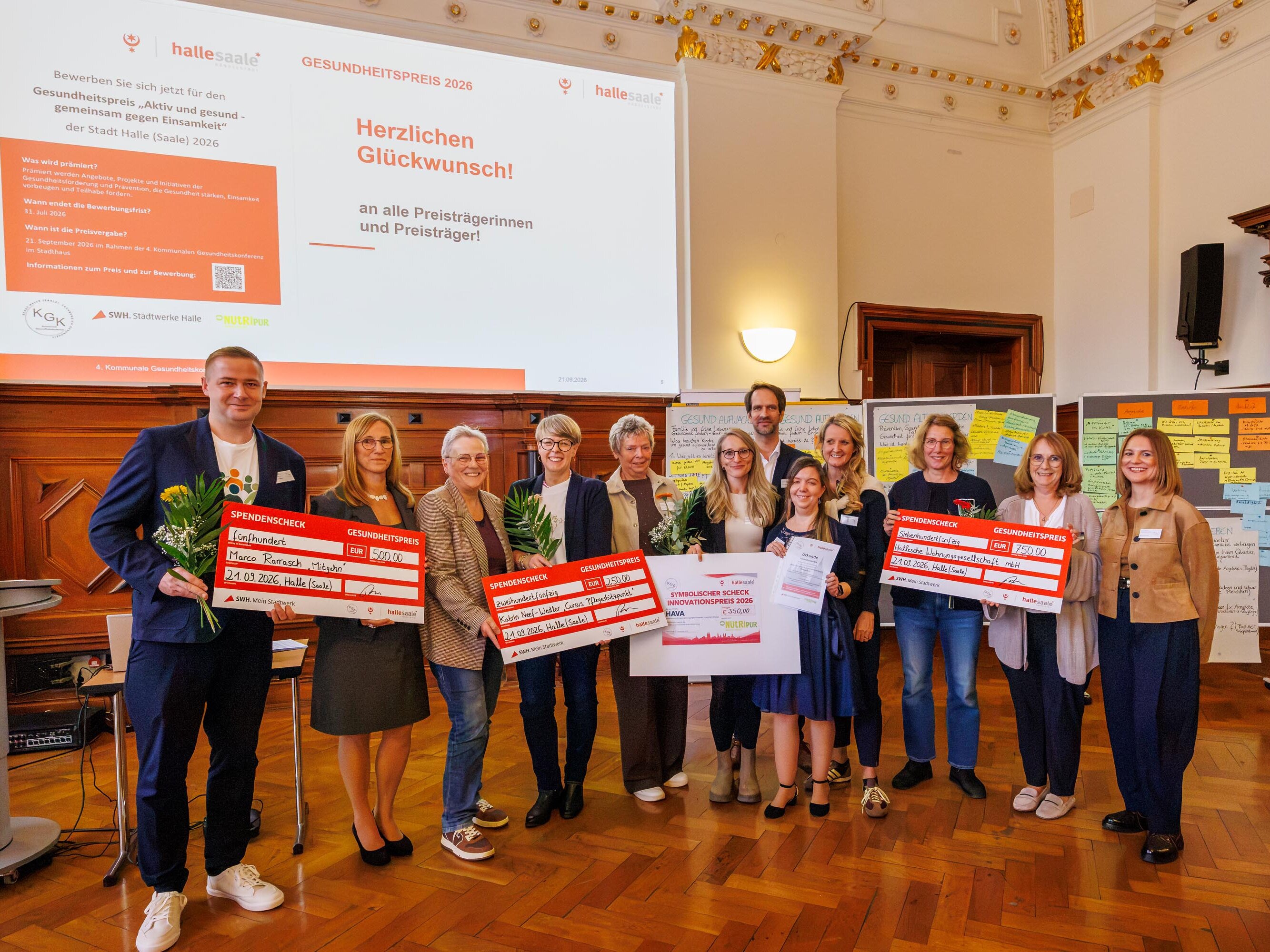 Gruppenfoto der Ausgezeichneten des Gesundheitspreises 2026 der Stadt Halle (Saale) mit Blumen und Preischecks bei der 4. Kommunalen Gesundheitskonferenz.