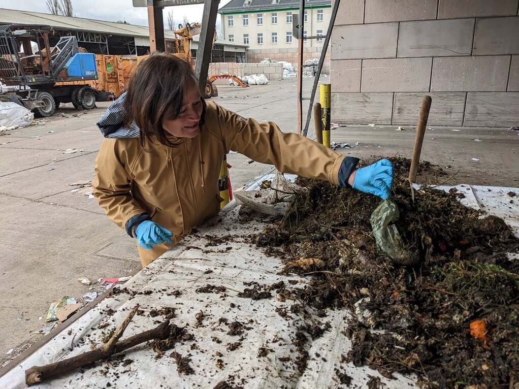 Frau sortiert Plastik aus dem Biomüll
