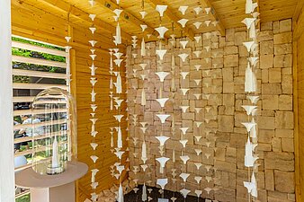 weiße Figuren wie z. B. der Rote Turm hängen in einer Holzütte aufgefädelt von der Decke