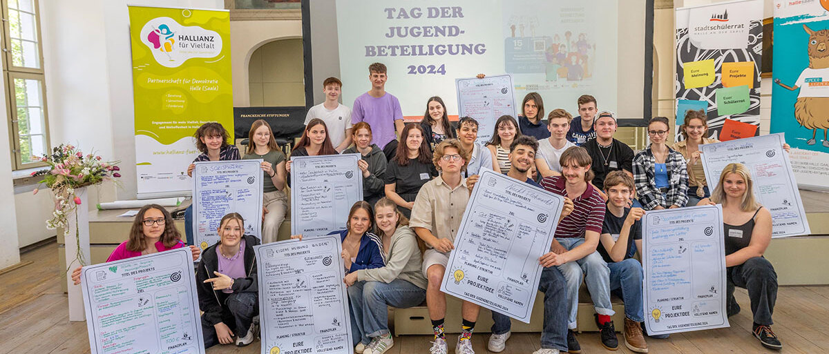 Eine Gruppe von Jugendlichen mit Ihren Plakaten mit Projektideen in der Hand in einem Saal der Franckeschen Stiftungen