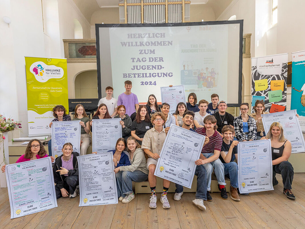 Eine Gruppe von Jugendlichen mit Ihren Plakaten mit Projektideen in der Hand in einem Saal der Franckeschen Stiftungen