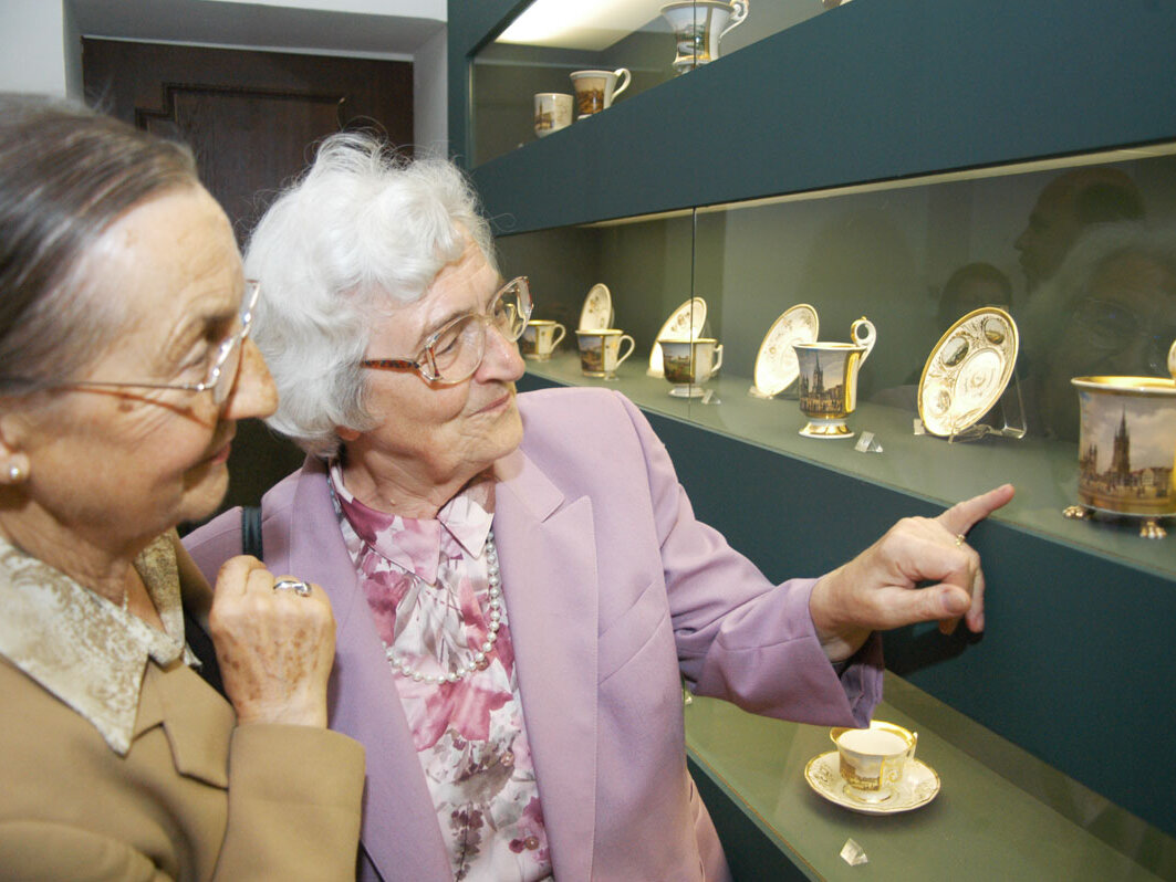 2 ältere Frauen schauen sich eine Porzellantasse im Museum an
