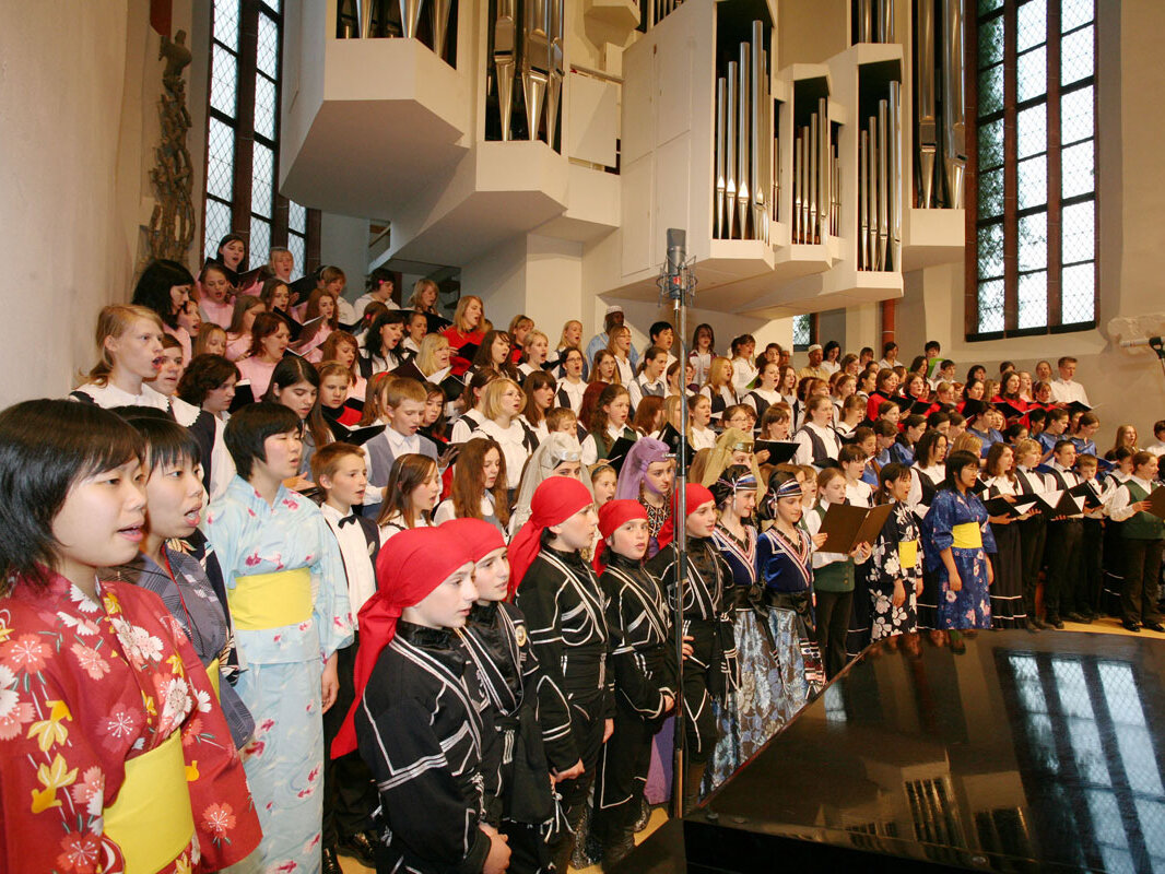 Kinder aus verschiedenen Ländern singen zusammen vor einer Orgel stehend