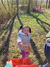 Kleines Mädchen legt gesammelten Streumüll in den Müllsack.
