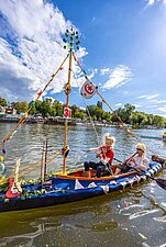 Mädchen spielt Geige auf einem bunt geschmückten Boot