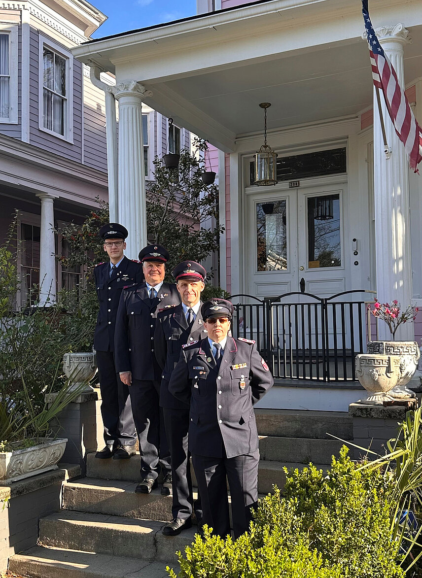 Vier Menschen in Feuewehruniform vor einem Haus