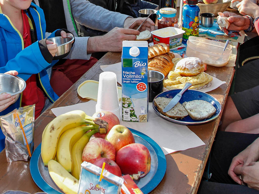 Blick auf einen gedeckten Frühstückstisch mit Obst, Milch und verschiedenem Gebäck