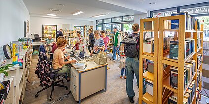 Mehrere Nutzerinnen und Nutzer betreten die neuen Räume der Stadtteilbibliothek Süd am Platz der Völkerfreundschaft in der Südstadt. 