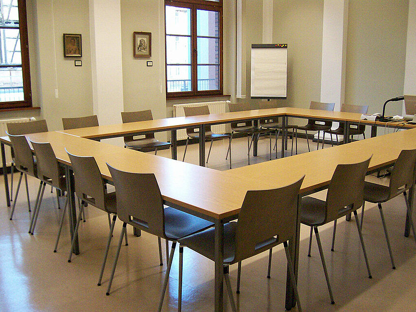 Blick in den Seminarraum mit Tischen und Stühlen