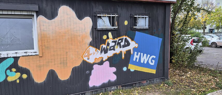Bunt gestaltete Wand eines Flachbaus mit HWG-Symbol