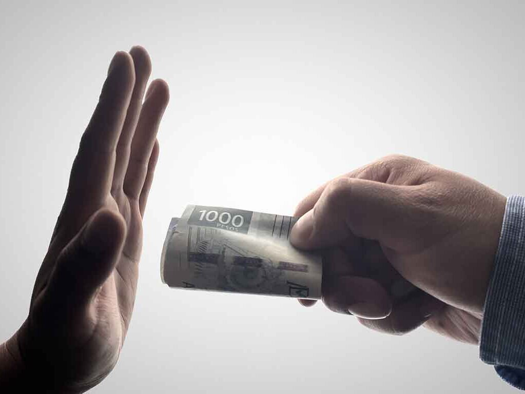 Eine Hand reicht einer anderen Hand einen Geldschein. Die zweite Hand lehnt ab