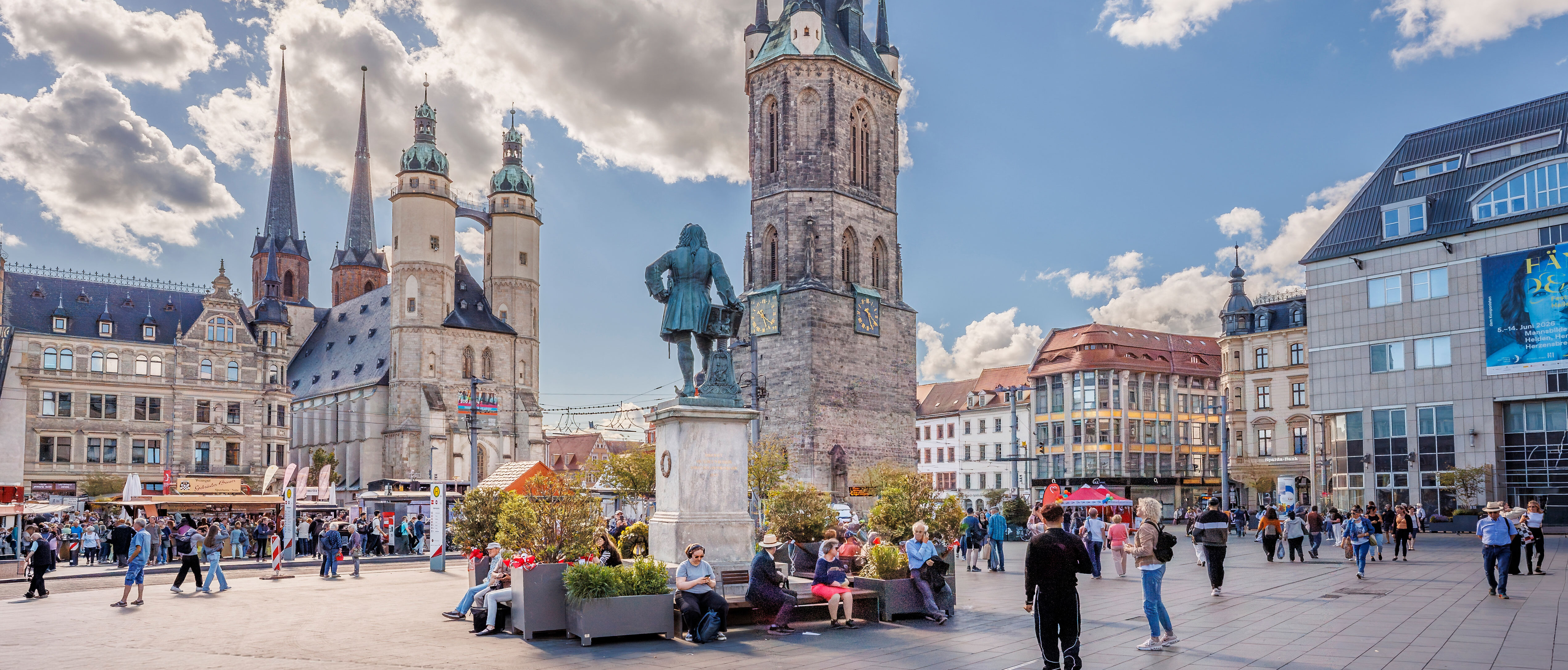 Marktplatz mit den fünf Türmen, am Himmel dicke weiße Wolken, hinter einer lugt die Sonne hervor
