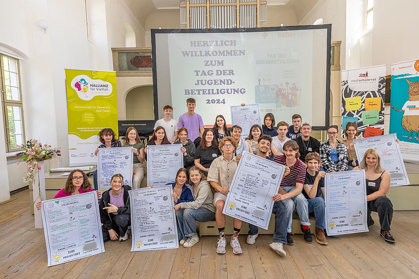 Gruppe von Jugendlichen im Freylinghausen-Saal der Franckeschen Stiftungen. Sie halten Plakate mit verschiedenen Projektideen, die in den nächsten Wochen umgesetzt werden sollen.
