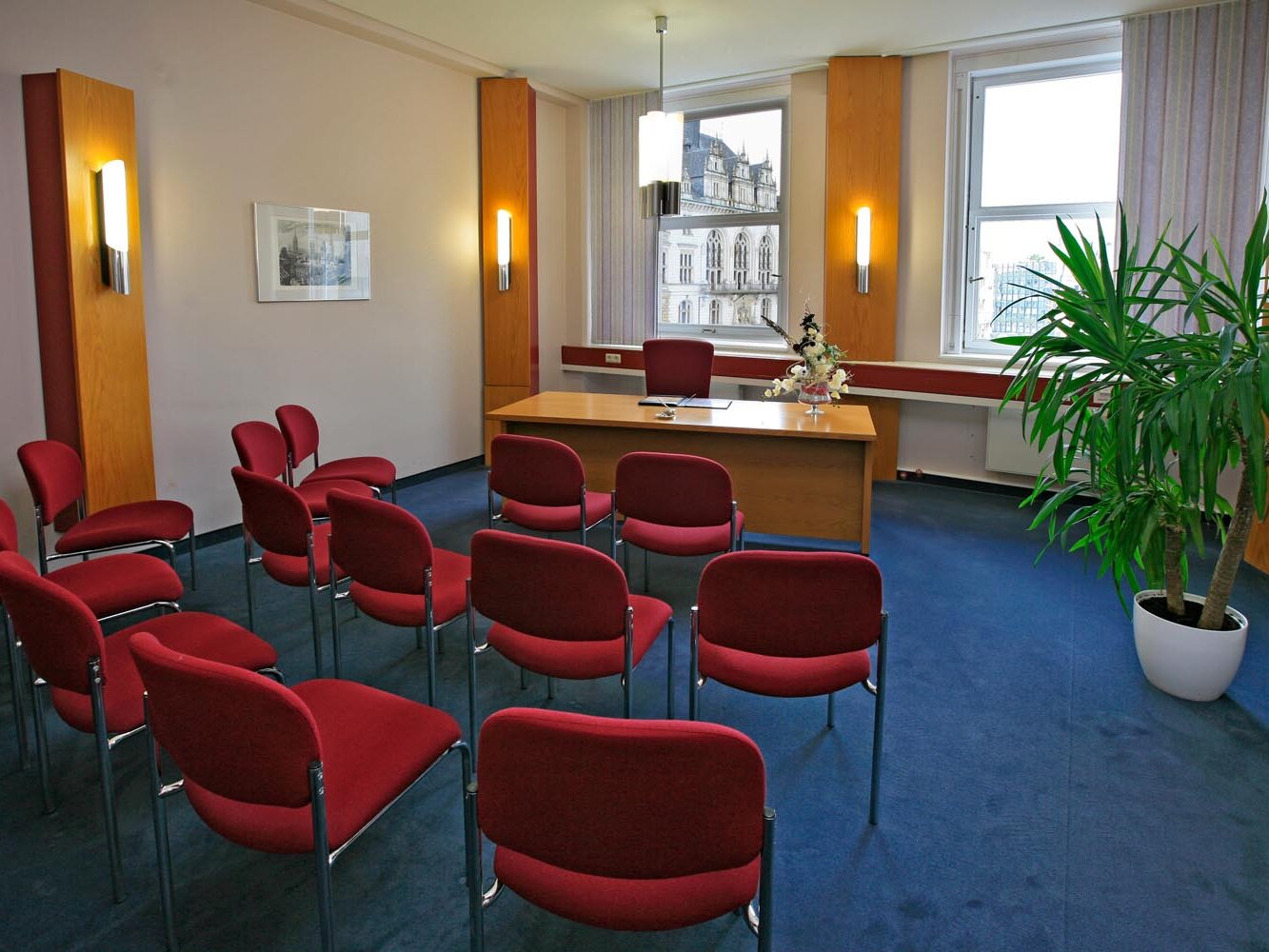 Blick in das Eheschließungszimmer im Ratshof, 13 leere rote Stühle, blauer Teppich, rechts eine Grünpflanze