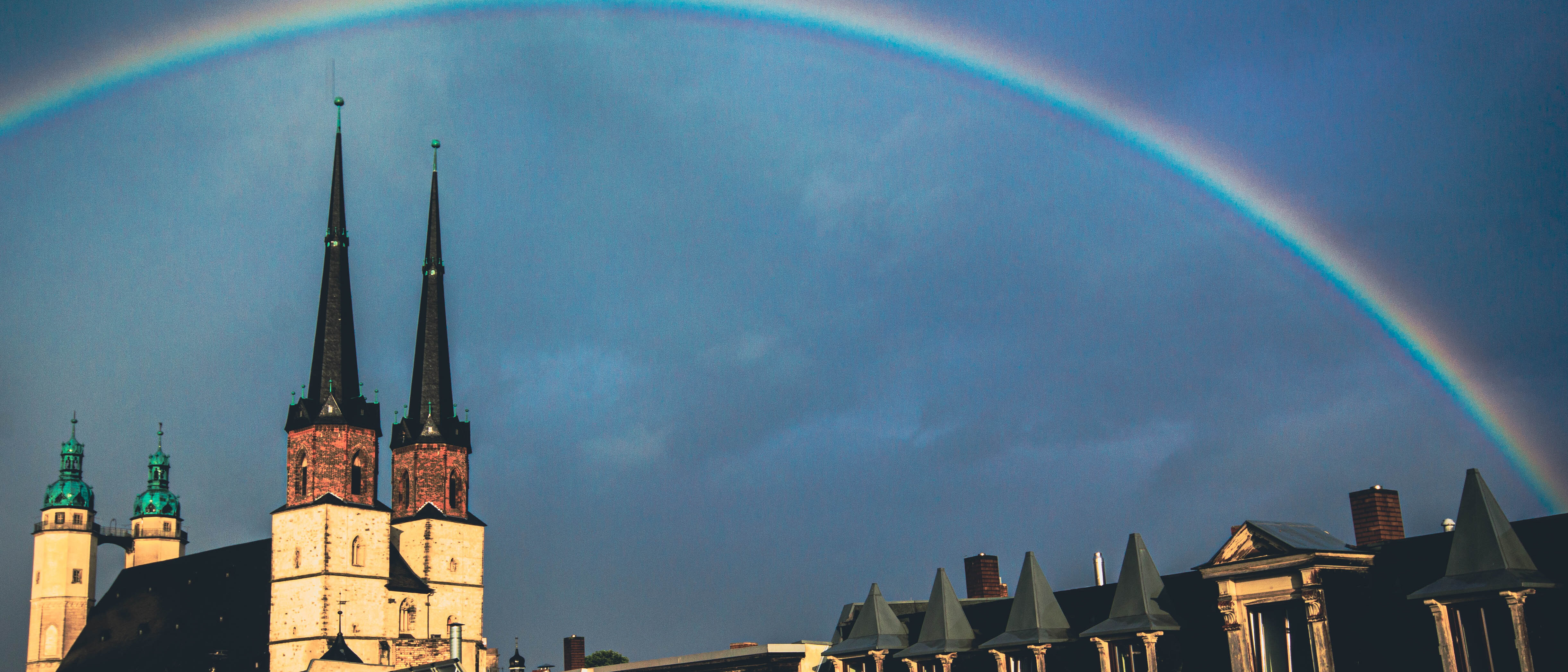 Bild über den Dächern der Stadt Halle mit Marktkirche und Regenbogen
