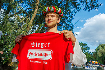 Hallore mit Siegerkranz und rotem T-Shirt mit der Aufschrift "Sieger Fischerstechen Laternenfest 2026"