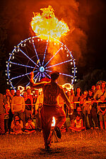 Feuershow eines Gauklers, im Hintergrund beleuchtetes Riesenrad
