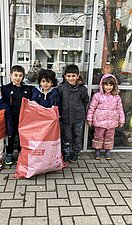 Vier Kinder stehen vor der Kita und halten einen befüllten Müllsack in der Hand.