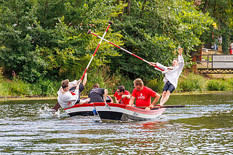 2 Halloren auf Booten stooßen sich mit großen Stangen gegenseitig ins Wasser