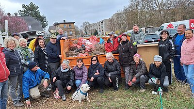 Gruppenfoto bestehend aus mehreren Beteiligten der Initiative, die vor einem befüllten Container stehen.